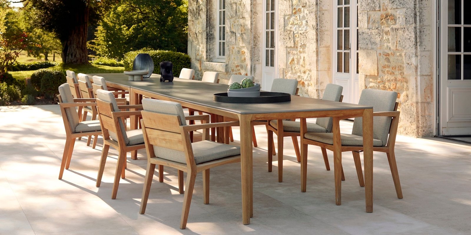 Sodobna vrtna garnitura na terasi z mizo in stoli v naravnem ambientu